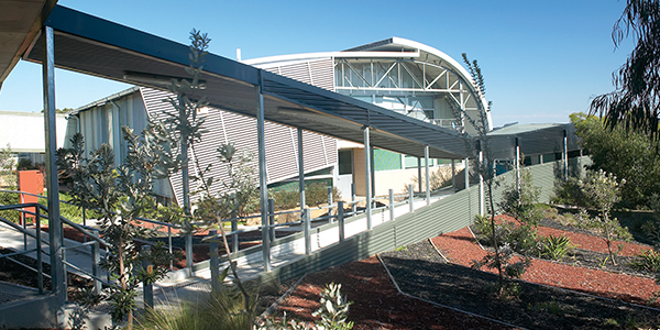 External fascade of metal building with ramp leading to entrance and garden beds