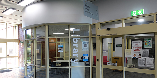 front of glass library with 'library' written on glass.